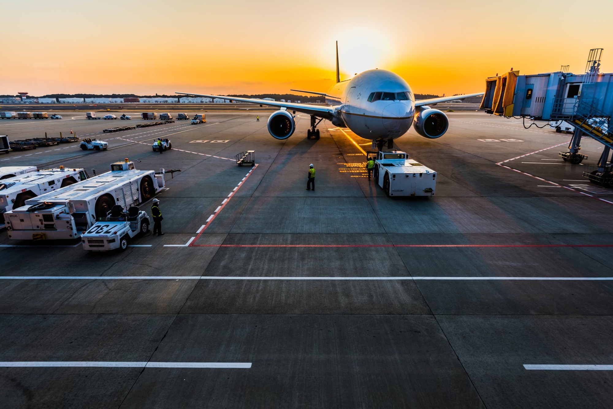 Passenger aircraft, ground crews, service vehicles, and jet bridge operating together at an airport gate